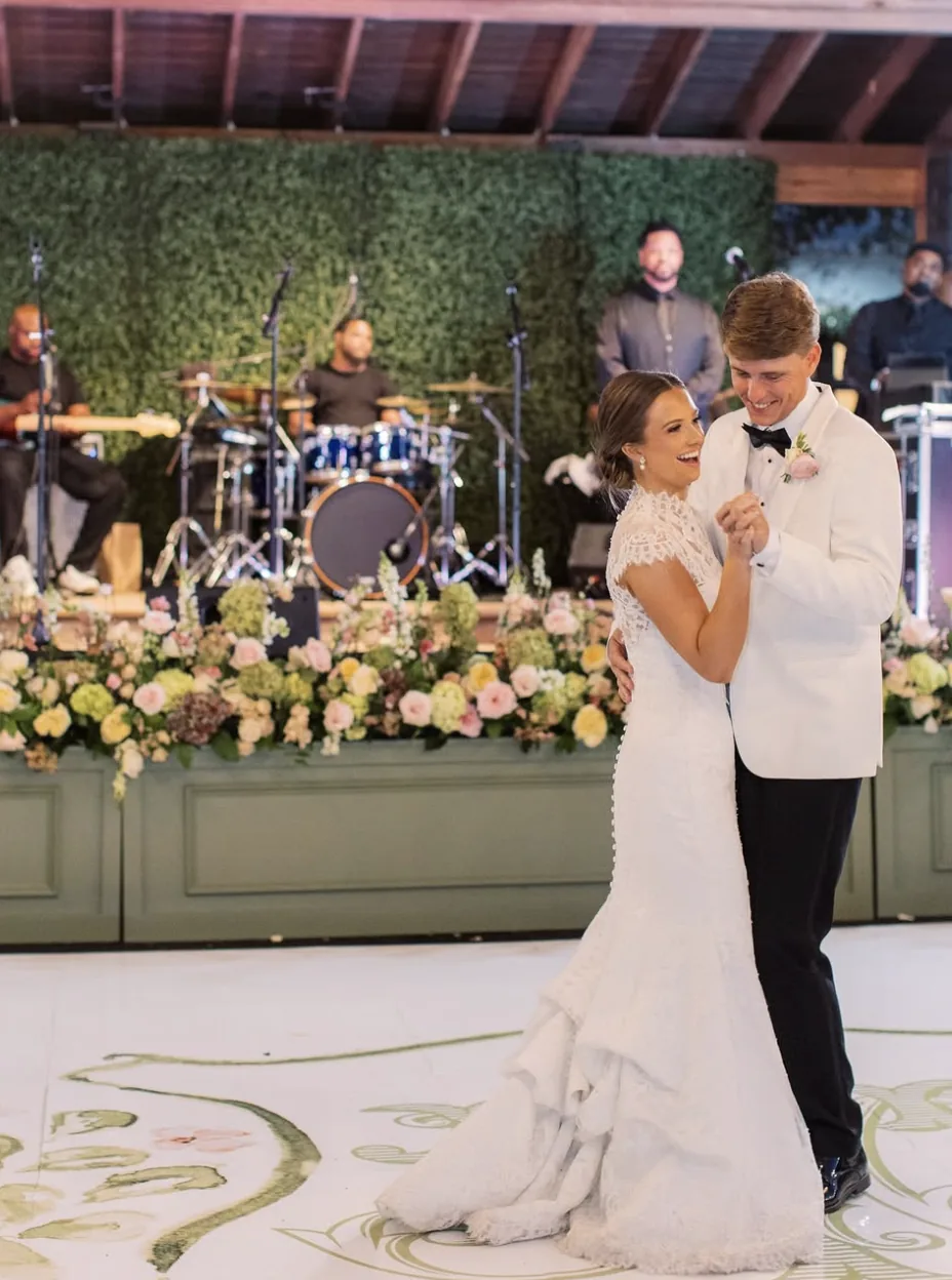The couple's first dance in front of a greenery and floral stage backdrop