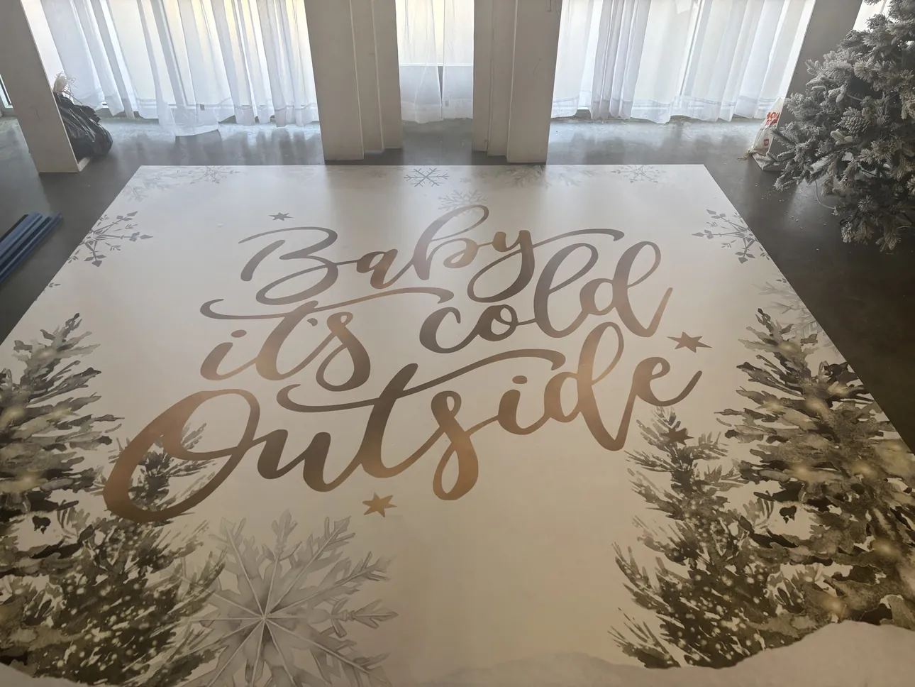 A white and gold Baby It's Cold Outside dance floor wrap with snowy pines