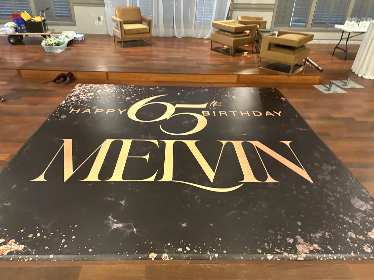 A black and gold dance floor wrap reading Happy 65th Birthday Melvin