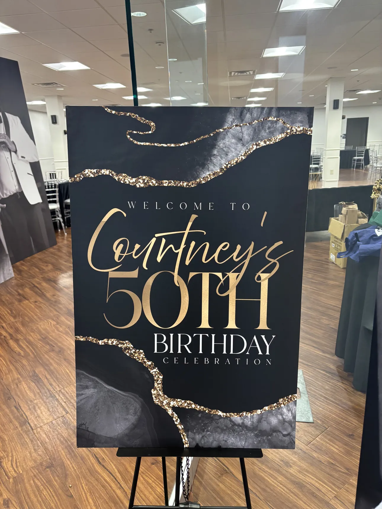 A black and gold welcome sign for Courtney's 50th birthday on an easel