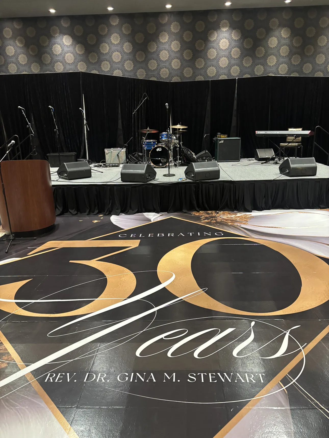 A black and gold Celebrating 30 Years floor wrap for Rev. Dr. Gina M. Stewart