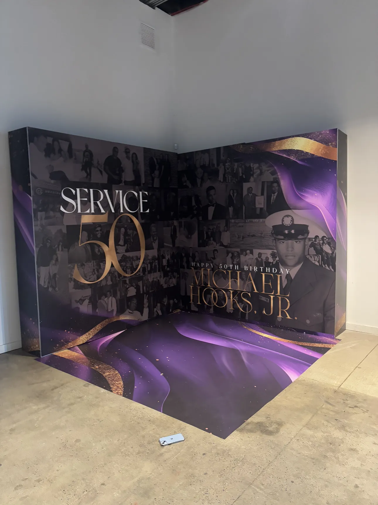 A purple and gold Service 50 corner backdrop with photos