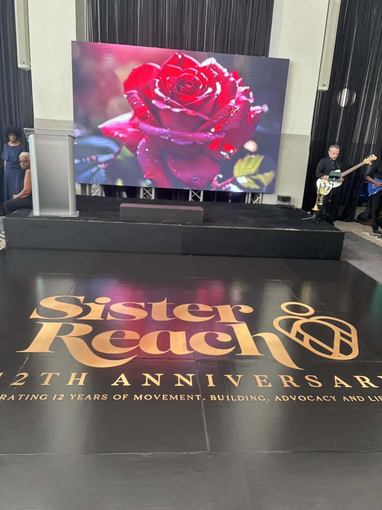 A Sister Reach 12th Anniversary floor wrap in front of the stage