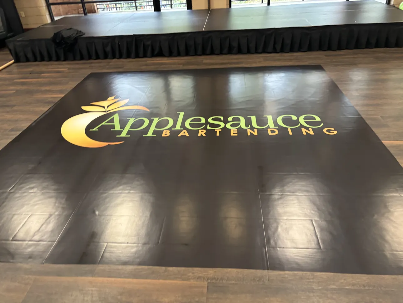 A black Applesauce Bartending logo floor wrap