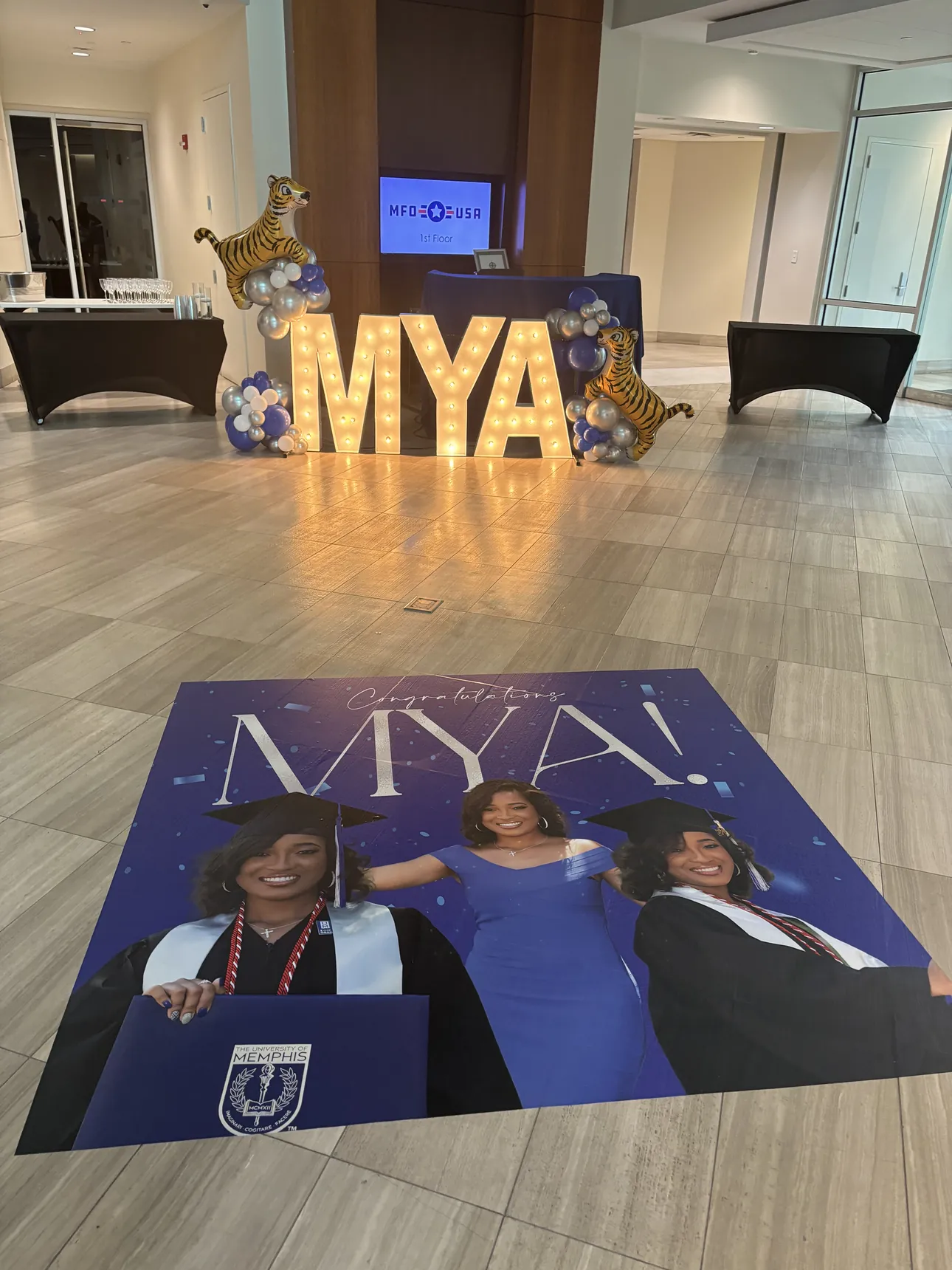 A blue Congratulations Mya floor wrap with her University of Memphis graduation photos